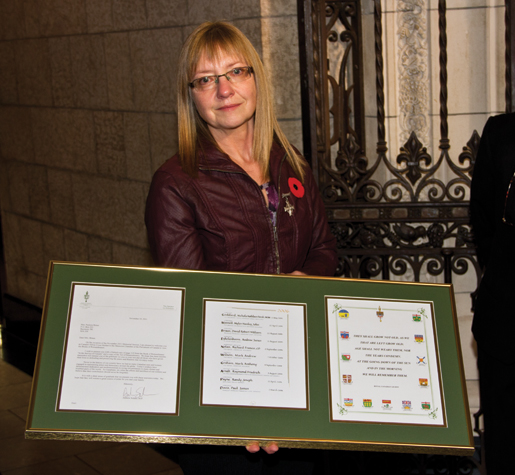 La mère de la Croix d’argent, Patty Braun, reçoit une page d’un Livre du Souvenir. [PHOTO : TOM MacGREGOR]
