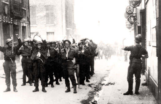 Un soldat allemand fait signe à des soldats canadiens récemment capturés qui font la queue dans la rue. [PHOTO : CONSEIL RÉGIMENTAIRE DU ROYAL HAMILTON LIGHT INFANTRY]