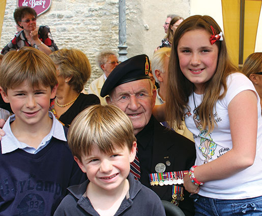 Le vétéran du débarquement Bud Hannam est entouré d’enfants français avant une cérémonie à Basly (France). [PHOTO : SHARON ADAMS]
