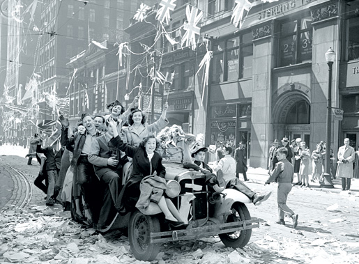 Des jeunes agitent des drapeaux et donnent des coups de klaxon en se joignant à la fête le long de la rue Bay, à Toronto. [ARCHIVES DE LA VILLE DE TORONTO/96241]